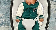 Myles is registered to the contest to win money with this photo: baby, baby_rocker, baby_seat, carpet, child, comfort, cute, expression, face, flooring, green_clothing, home_interior, indoor, infant, modern_furniture, person, sitting, white_clothing, wood_floor, young_child