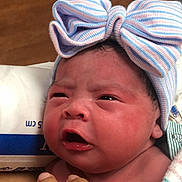 Alizae is registered to the contest to win money with this photo: baby, newborn, infant, bow, hat, hand, blanket, face, skin, newborn_baby, expression, cute, indoors, portrait, person, headwear, holding, closeup, sleepy, soft