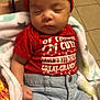 baby, sleeping, red_headband, red_shirt, text_on_shirt, denim_jeans, ripped_jeans, blanket, indoor, tiled_floor, cute, child, infant, cozy, hand, casual_clothing, portrait, peaceful, resting, young_child
