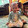 baby, carpet, cat_design, child, clothing, face, furniture, home, indoors, living_room, patterned_clothing, portrait, sitting, skirt, sofa, sunlight, sweater, table, toddler, window