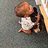 toddler, child, dog, pet, hugging, smiling, happy, indoor, carpet, floor, sitting, cuddling, animal, black_dog, white_clothing, patterned_clothing, barefoot, portrait, overhead_view, home