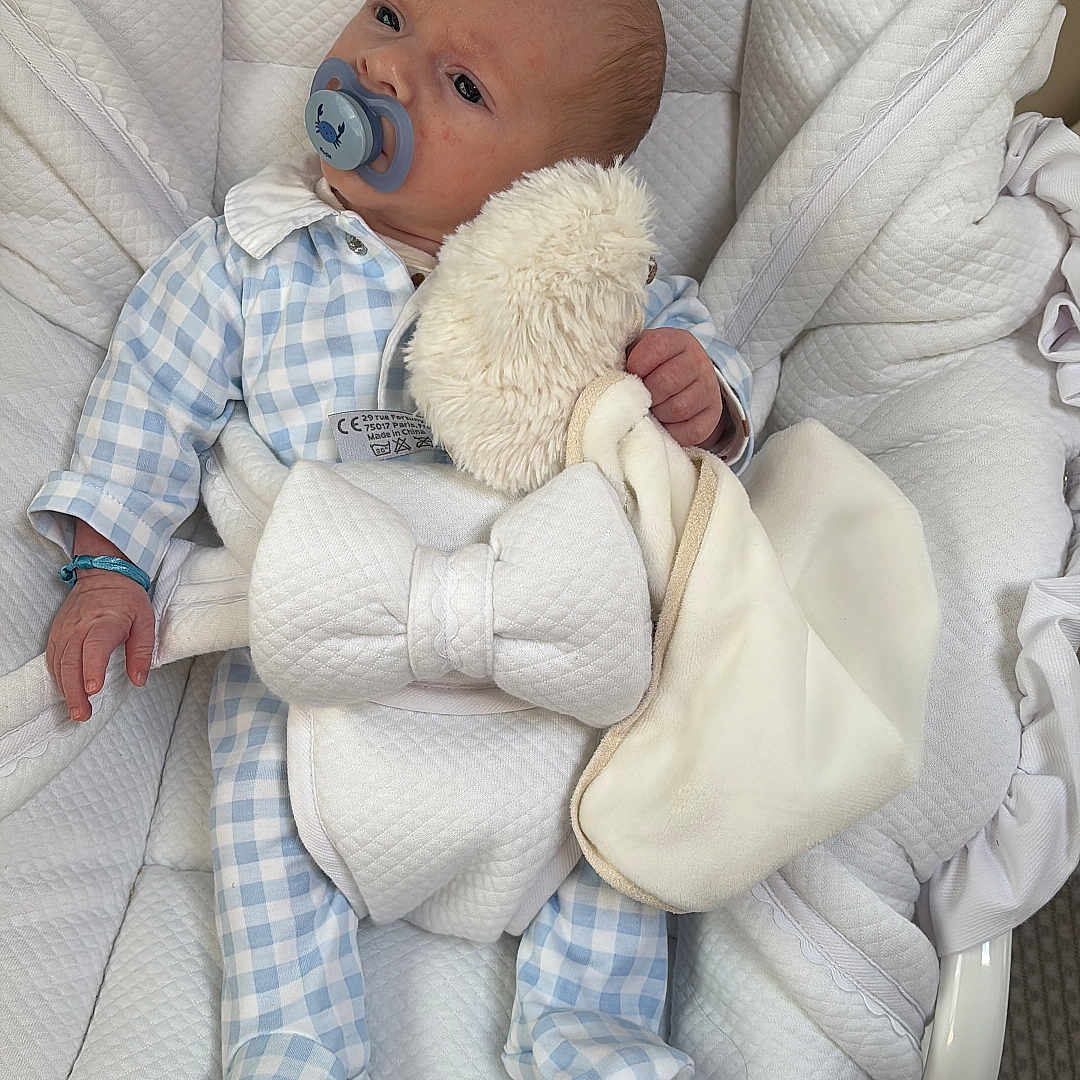 Gabriel participe au concours pour gagner de l'argent avec cette photo : baby, bassinet, blanket, blue, clothing, comfort, face, hand, head, indoor, infant, onesie, pacifier, person, quilted, resting, sleepwear, soft_toy, stuffed_toy, white