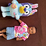 Rugvednandan joined the competition — help win amazing prizes! baby, infant, stuffed_animal, plush_toy, blanket, smile, lying_down, bracelet, shorts, pink_shirt, blue_shorts, toy, happy, portrait, barefoot, fabric, playtime, cartoon, home, cozy