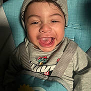 Ashton joined the competition — help win amazing prizes! toddler, child, laughing, smiling, face, beanie, hat, clothing, seat, safety_strap, indoors, happy, cute, person, young_child, expression, apparel, headwear, baby, joy