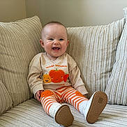 Paisley joined the competition — help win amazing prizes! baby, child, smiling, couch, pillows, sitting, indoors, clothing, leggings, shoes, pumpkin, happy, face, cute, infant, cozy, texture, striped, comfortable, portrait