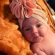Isabella is registered to the contest to win money with this photo: baby, infant, headwrap, pink, blanket, orange, soft_texture, cute, portrait, face, skin, newborn, lying_down, indoors, expression, child, adorable, closeup, person, cozy