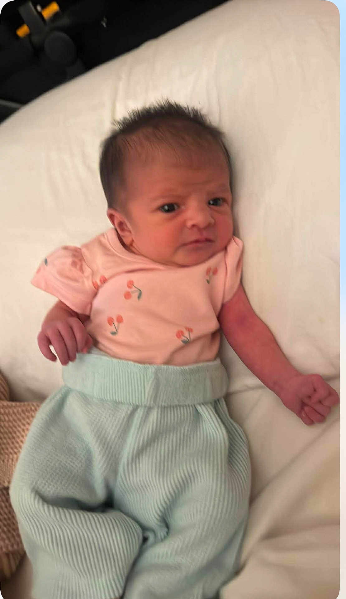 Story is registered to the contest to win money with this photo: baby, newborn, infant, child, person, clothing, pink_shirt, blue_pants, lying_down, bed, blanket, soft, cute, face, hand, hair, skin, indoors, portrait, expression