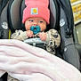 baby, car_seat, pacifier, pink_beanie, blanket, mickey_mouse, clothing, infant, cute, indoor, child, seatbelt, shopping_aisle, soft_toys, warm_clothes, newborn, face, person, comfort, bundle