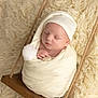 Liam participe au concours pour gagner de l'argent avec cette photo : newborn, baby, sleeping, swaddled, blanket, hat, pom_pom, wooden_swing, rope, fluffy, soft_texture, cream_color, peaceful, portrait, infant, close_up, cozy, resting, cute, indoors