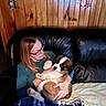 woman, puppy, dog, saint_bernard, couch, leather, blanket, glasses, wood_paneling, indoor, pet, holding, seated, comfort, casual_clothing, relaxation, cozy, fur, cute, love
