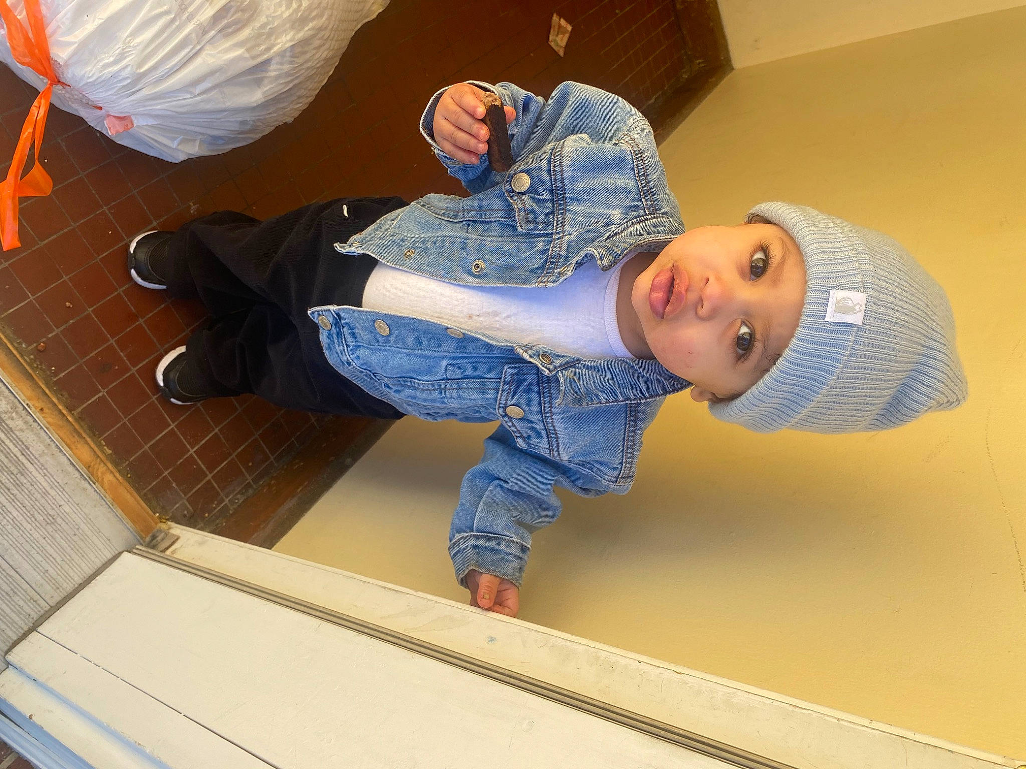 Josiah is registered to the contest to win money with this photo: baby, baby_toddler_clothing, cap, child, comfort, denim, elbow, electric_blue, flooring, headgear, headwear, leisure, linens, person, plastic_bag, room, sitting, sleeve, toddler, wood