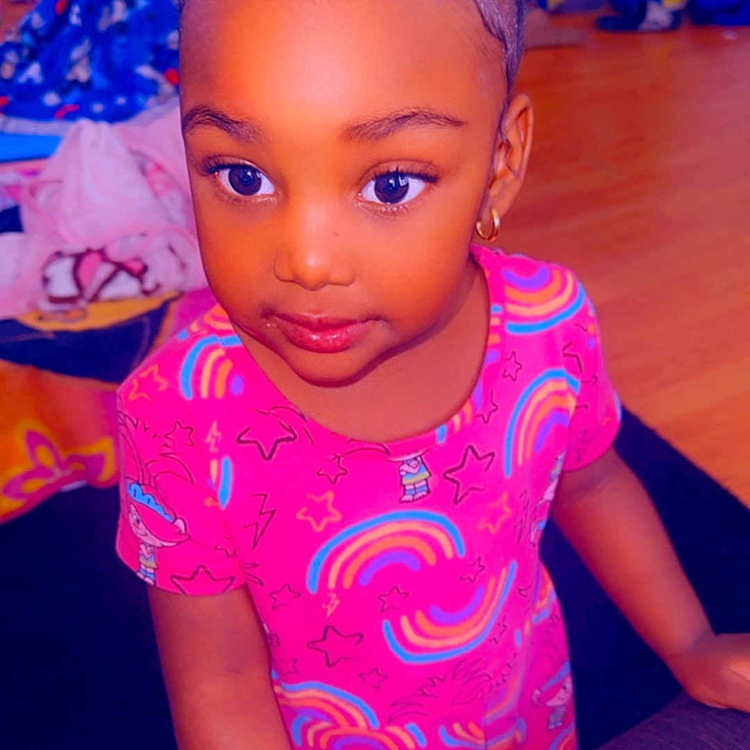 Kali joined the competition — help win amazing prizes! blanket, bright_eyes, child, colorful_clothing, curious, earrings, furniture, hair_accessory, indoor, person, pink_dress, portrait, rainbows, room, stars, table, toddler, toys, wooden_floor, young_child