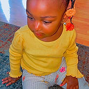 Kali joined the competition — help win amazing prizes! toddler, child, girl, sitting, yellow_top, floral_pants, braided_hair, beads, indoor, rug, floor, curious, cute, portrait, clothing, hand, skin, person, young_child, playful