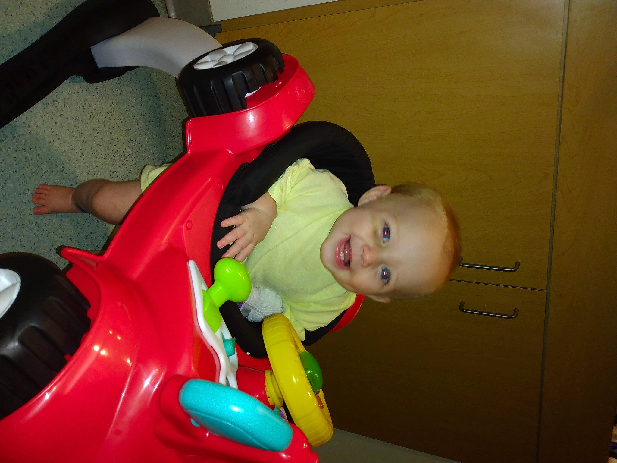 Audreya is registered to the contest to win money with this photo: baby, baby_products, baby_toddler_clothing, baby_toys, carmine, child, flooring, fun, joy, person, plastic, play, riding_toy, room, sitting, tire, toddler, toy, toy_vehicle, wheel