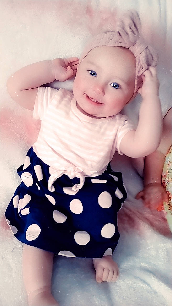 Audreya is registered to the contest to win money with this photo: arm, baby, baby_toddler_clothing, day_dress, dress, finger, flash_photography, gesture, hand, happy, headgear, headwear, joy, one_piece_garment, person, photograph, pink, skin, sleeve, smile