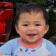 Tyson is registered to the contest to win money with this photo: child, toddler, smiling, shopping_cart, clothing, receipt, car, vehicle, outdoor, greenery, face, happy, person, cute, baby, patterned_clothing, sleeves, holding, daylight, portrait
