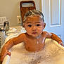 Tyson is registered to the contest to win money with this photo: baby, bathtub, bubbles, foam, bath, child, shampoo, soap, water, skin, face, hands, bathroom, door, wooden_board, curious, sitting, cleaning, indoor, toddler