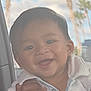 Tyson is registered to the contest to win money with this photo: baby, child, smiling, hands, car_interior, window, sky, palm_trees, white_clothing, portrait, cute, happy, infant, face, person, human_hand, outdoor_view, daylight, casual, closeup