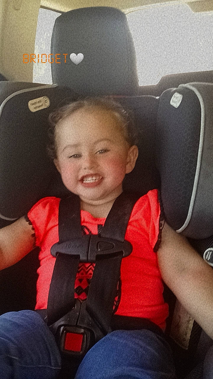Nevaeh is registered to the contest to win money with this photo: auto_part, automotive_design, cap, car_seat, car_seat_cover, comfort, face, finger, happy, head, head_restraint, joy, light, person, plant, seat_belt, smile, steering_part, steering_wheel, thumb