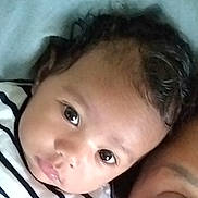 Mayna participe au concours pour gagner de l'argent avec cette photo : baby, child, face, curly_hair, striped_shirt, closeup, portrait, resting, shoulder, person, skin, eyebrows, eyes, infant, cute, young, indoor, head, expression, human