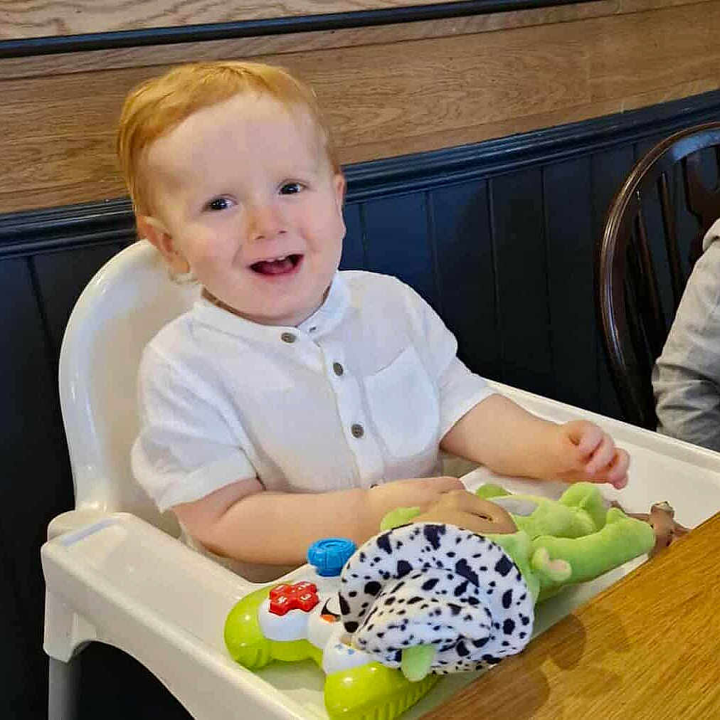 Elliot joined the competition — help win amazing prizes! baby, casual, child, cute, face, furniture, happy, high_chair, indoor, person, playful, red_hair, seat, smiling, table, toddler, toy, white_clothing, wood, young_child