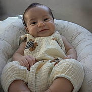 Noah Aurelius joined the competition — help win amazing prizes! baby, smile, cushion, chair, infant, clothing, foot, hand, face, giraffe_print, pattern, comfortable, cute, indoors, portrait, child, relaxed, soft_light, happy, seated