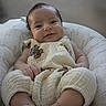 baby, smile, cushion, chair, infant, clothing, foot, hand, face, giraffe_print, pattern, comfortable, cute, indoors, portrait, child, relaxed, soft_light, happy, seated