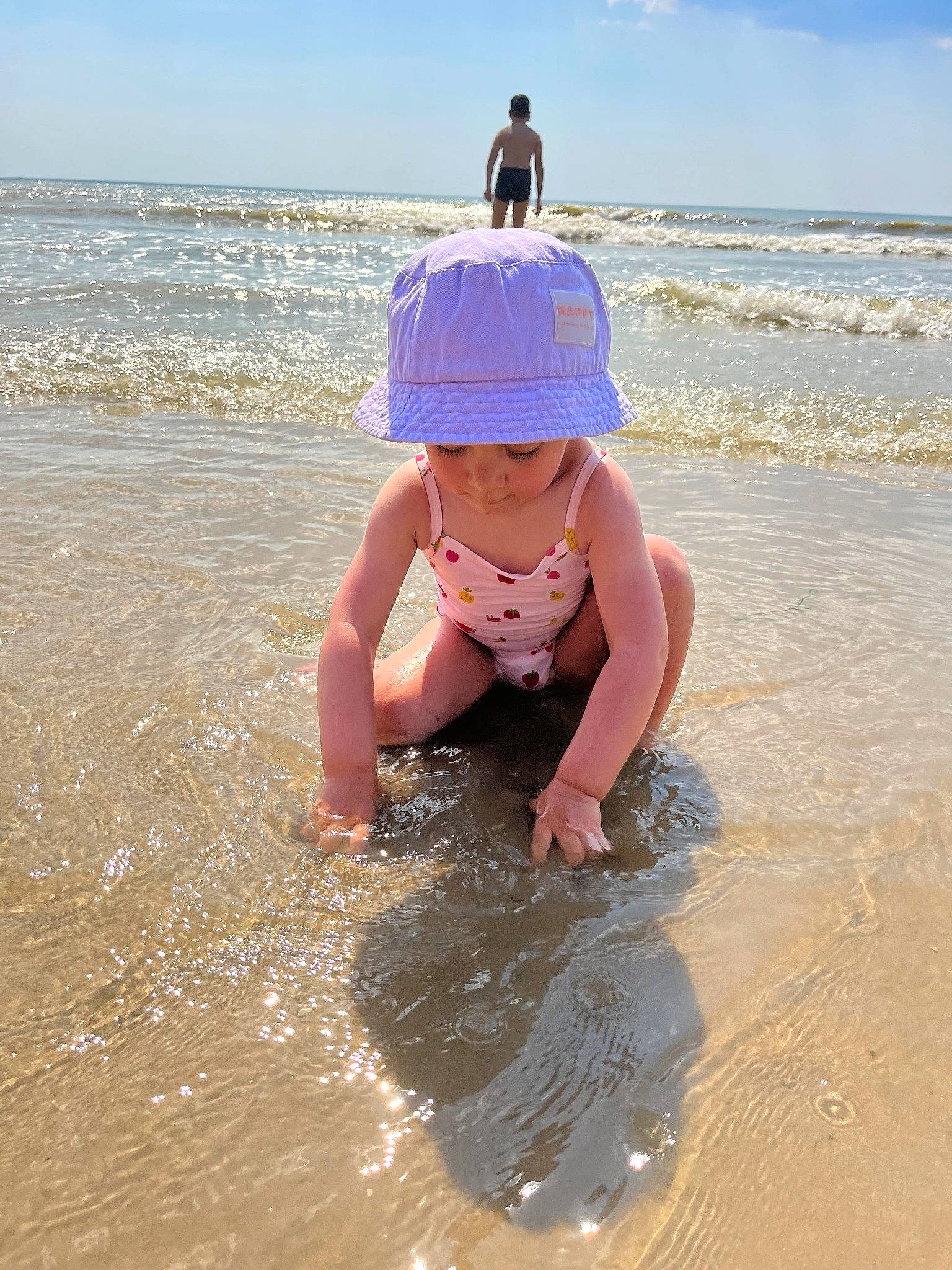 Lyna participe au concours pour gagner de l'argent avec cette photo : barefoot, bathing, beach, cloud, fun, happy, hat, headgear, headwear, leisure, people_on_beach, person, personal_protective_equipment, recreation, sand, shore, sky, summer, toddler, water