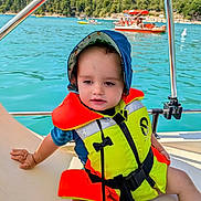 Marius a rejoint le concours — aidez-le/la à gagner de superbes lots ! toddler, life_jacket, hat, boat, water, lake, forest, trees, child, outdoor, summer, sun_hat, nature, recreation, vacation, safety, people, background, blue_sky, relaxation
