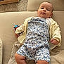 baby, infant, child, couch, sofa, clothing, romper, cardigan, toy, striped_toy, plush_toy, beige, fabric, texture, indoor, person, relaxed, lying_down, cute, portrait