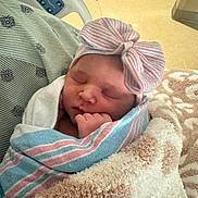 Stori joined the competition — help win amazing prizes! baby, newborn, infant, sleeping, hospital, blanket, swaddle, striped_hat, bow, hand, cozy, portrait, close_up, hospital_bed, gown, soft_texture, peaceful, newborn_hat, child, medical