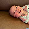 baby, smiling, happy, infant, portrait, face, child, pink_shirt, striped_clothing, couch, leather_surface, closeup, cute, young_child, skin, head, eyes, mouth, expression, relaxed