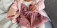 Lola participe au concours pour gagner de l'argent avec cette photo : baby, infant, pink_cardigan, floral_skirt, white_tights, cushion, bed, blanket, soft_fabric, indoors, newborn, person, cute, child, resting, cozy, portrait, small_hands, sleepy_eyes, comfort