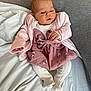 baby, infant, pink_cardigan, floral_skirt, white_tights, cushion, bed, blanket, soft_fabric, indoors, newborn, person, cute, child, resting, cozy, portrait, small_hands, sleepy_eyes, comfort