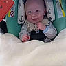 baby, smiling, blanket, car_seat, infant, child, toy, watermelon, seatbelt, happy, face, clothing, indoor, person, head_support, cute, safety, comfort, young_child, portrait