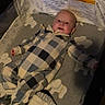 baby, crib, blanket, onesie, patterned, infant, sleeping_area, soft_toys, face, head, clothing, indoors, baby_bed, comfort, resting, child, person, baby_sleepwear, warm, cozy