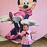 child, toddler, baby, smiling, standing, indoor, portrait, minnie_mouse, cartoon_character, pink, dress, shirt, shorts, barefoot, toy, backdrop, birthday, playful, happy, photography