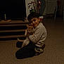 child, boy, cat, indoor, carpet, floor, furniture, smile, hug, pet, home, television, plant, shoe, casual_clothing, radiator, chair, toy, cozy, dim_light