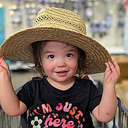 Savannah is registered to the contest to win money with this photo: toddler, child, hat, straw_hat, shopping_cart, black_tshirt, flowers, text, rosy_cheeks, smiling, curious_eyes, indoor, store, aisle, holding_hat, cute, happy, portrait, short_hair, casual_clothing