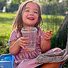 child, girl, smile, happy, outdoor, daylight, plastic_cup, pink_dress, animal_print, chair, grass, sunlight, nature, face, person, casual, sitting, playful, joyful, relaxed