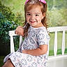Savannah is registered to the contest to win money with this photo: child, girl, smile, pink_bow, dress, bench, outdoor, portrait, happy, cute, hair, young, person, sitting, nature, greenery, background, casual, fashion, childhood