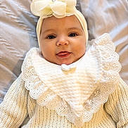 Sienna joined the competition — help win amazing prizes! baby, infant, face, headband, flower, knitwear, bib, smile, tongue_out, cute, portrait, child, clothing, texture, soft_light, indoor, person, closeup, happy, young