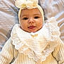 baby, infant, face, headband, flower, knitwear, bib, smile, tongue_out, cute, portrait, child, clothing, texture, soft_light, indoor, person, closeup, happy, young