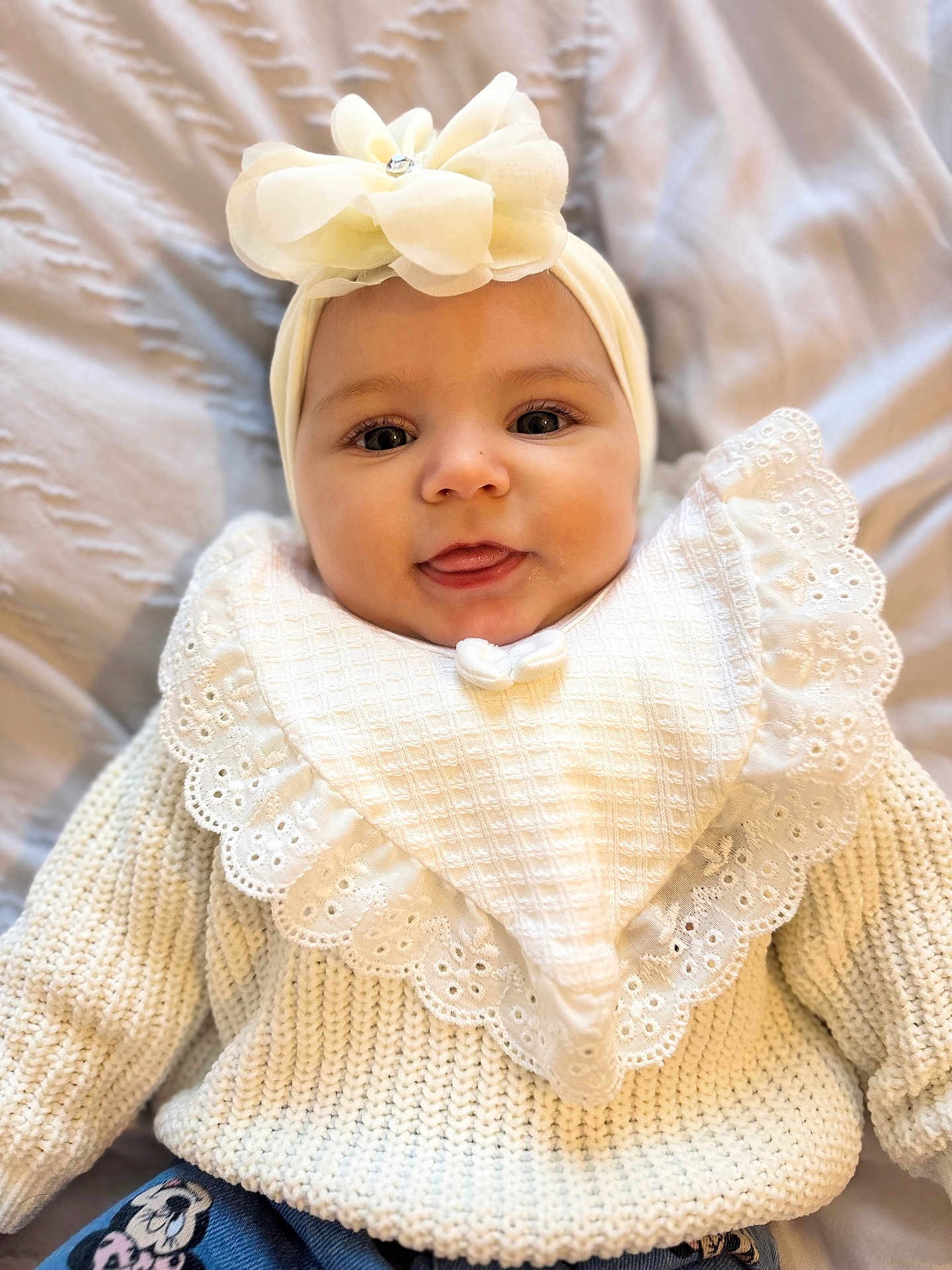 Sienna joined the competition — help win amazing prizes! baby, infant, face, headband, flower, knitwear, bib, smile, tongue_out, cute, portrait, child, clothing, texture, soft_light, indoor, person, closeup, happy, young