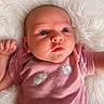baby, infant, pink_clothing, bunny_print, onesie, fluffy_blanket, curious_expression, cute, newborn, lying_down, human, small_hands, soft_texture, indoors, portrait, head, face, skin, child, adorable