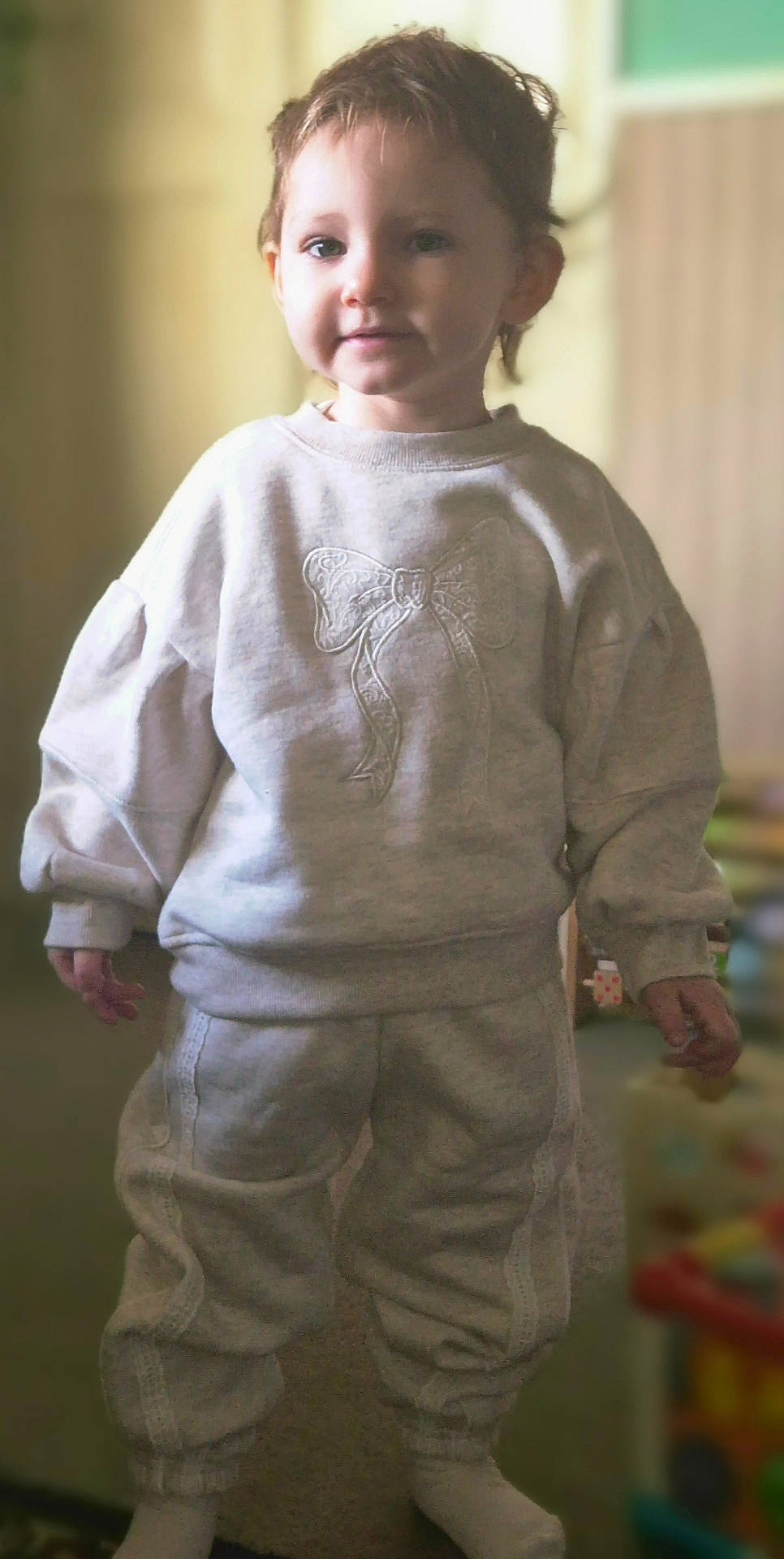 Skylar-Rose joined the competition — help win amazing prizes! blurred_background, casual_wear, child, clothing, cozy, cute, face, hair, home, indoor, pants, person, portrait, smile, socks, soft_light, standing, sweatshirt, toddler, young_child