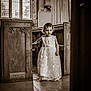 child, girl, dress, church, wooden_pews, window, light, stone_floor, cross_necklace, interior, vintage, curly_hair, standing, portrait, sepia, religious, architecture, young, solemn, decorative