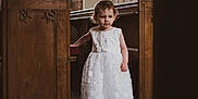 Skylar-Rose joined the competition — help win amazing prizes! child, toddler, white_dress, church, pew, wooden_furniture, natural_light, window, floor, portrait, indoor, ceremony, cute, girl, floor_tiles, cross_necklace, curly_hair, standing, dress, solemn