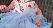 Cali joined the competition — help win amazing prizes! baby, infant, headband, tutu, blue_tutu, onesie, patterned_clothing, lying_down, blanket, soft_texture, cute, child, small_person, smiling, indoors, portrait, playful, adorable, baby_girl, headwear