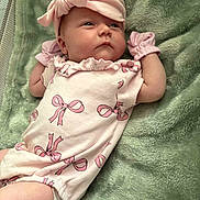 Cali joined the competition — help win amazing prizes! baby, infant, onesie, pink_bow, headband, mittens, blanket, soft_texture, lying_down, curious_expression, cute, newborn, child, indoors, portrait, clothing, fabric, person, sleepwear, cozy